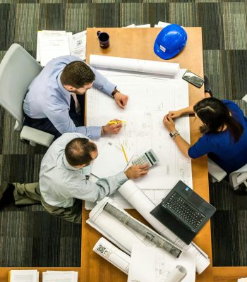 Top view of a team working on construction plans in an office setting.